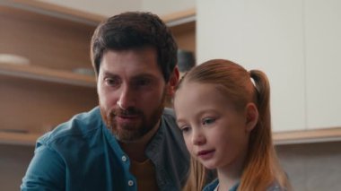 Mutfaktaki beyaz mutlu aile, küçük kız evlat edinilmiş velayet çocuğu, evde eğitim görmüş bilgisayar eğitimi almış baba dizüstü bilgisayarın teslimatı sırasında meyve suyu kullanmasına yardım etmiş.