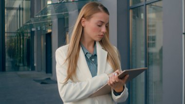 Düşünceli Kafkas kadın öğrenci müdürü tabletli bir kadınla yürüyor ve problem üzerinde kafa yoruyor. Ciddi kız işçi parmak kaldırma çözüm bulma iş fikri şehir dışında daktilo cihazı ekranı