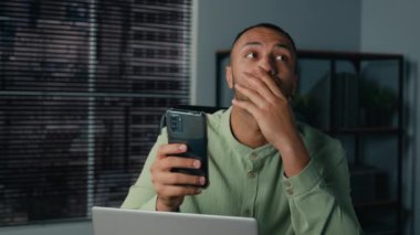 Sinir krizi, endişeli Afro-Amerikan iş adamı erkek girişimci çalışanın ofis işyerinde kötü haberler okumasına neden oldu. Kriz krizi, akıllı telefondaki yazılım hatası