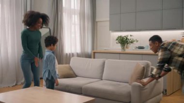 Mutlu Afro-Amerikan aile taşınması kadın anne çocuk çocuk çocuk baba mobilya taşınması kanepeye atlayıp yeni ev modern daire satın alma kutlamaları.