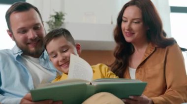 Anne baba oğul rahat oturma odasında kitap okuyorlar sevgi dolu ebeveynler peri masalı çocuk çocuk mutlu beyaz aile rahatlıyor hafta sonu hobi geliştirme eğitimi desteğinin keyfini çıkarıyorlar