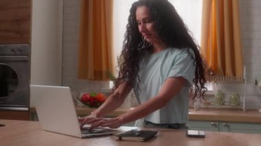 Mutlu gülümseyen beyaz kadın İspanyol kadın kadın kadın kadın ev mutfağında serbest çalışan iş kadını dizüstü bilgisayar daktilosu serbest çalışan internet işlerinde düşünceli gülümseme kullan bilgisayar çalış yemek siparişi ver