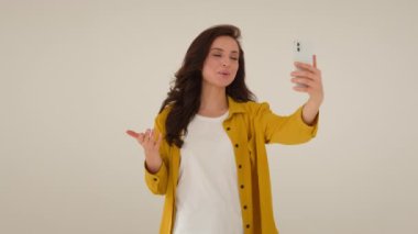 Gülümseyen Kafkasyalı kadın etkili blogcu video blogu çeken cep telefonu akıllı telefonu. Kız vlogger konuşma yürüyüşü. Stüdyo kıyafetlerinin canlı yayını evde canlı yayınlanıyor.