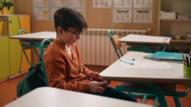 Okul eğitimi, beyaz erkek çocuk, liseli çocuk, okul öğrencisi, ders aleti bağımlısı cep telefonu bağımlısı, online video oyunu oynayan, masanın altında akıllı telefon saklayan çocuk.