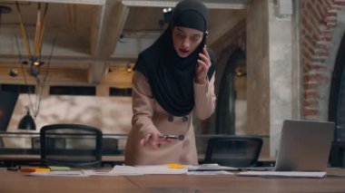 Arap müslüman kadın ofis bayan işkadını tesettür içinde islamik çoklu görev planlayıcısı iş planlamacılarıyla meşgul çıkartmalar yazıyorlar cep telefonu görüşmesi bilgisayarına danışmanlık.