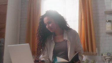 Gülümseyen İspanyol serbest kadın Latin kadın iş kadını serbest çalışan ev mutfağından uzakta çalışan iş bilgisayarında internet uygulaması kullanarak bilgisayar daktilo alışverişi yapan