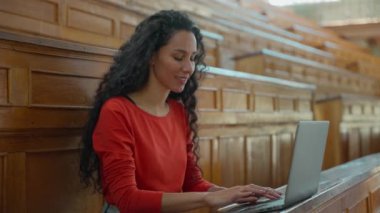Latin kadın, üniversite oditoryumunda Latin kız öğrenci. Bilgisayarda yazı yazma diploması. İnternette dizüstü bilgisayarla internetten eğitim öğrenme eğitimi alıyor.