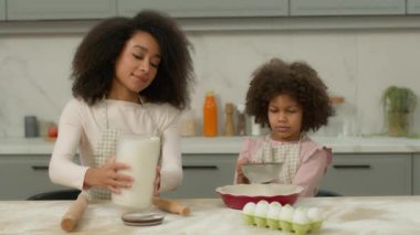 Afro-Amerikan ailesi hamurlu pizza tarifi yapar. Anne kadın birlikte yemek yapar. Küçük kız çocuğa un dökmeyi öğretir.