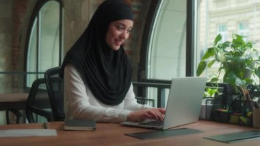 Kadın tesettürlü Müslüman kadın, Arap serbest işçi, iş kadını, ofis müdürü, bilgisayarlı, gülümseyen İslamcı iş kadını, iş yerindeki bilgisayarlı bilgisayarla uzaktan kumandalı iş kadını.
