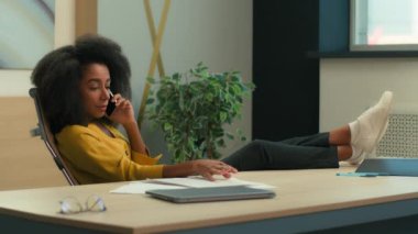 Afrika kökenli Amerikalı iş kadını ciddi işveren patronu iş adamı yönetici iş yerindeki cep telefonu konuşmaları masa başı kadın etnik kadın akıllı telefon konuşmaları