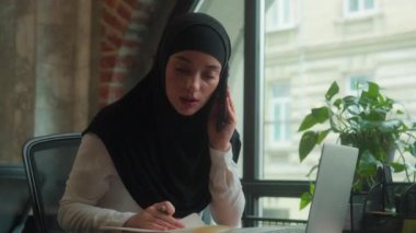 Arap Müslümanlar meşgul iş kadını tesettürlü İslamcı kadın ofis müdürü iş kadını birden fazla iş kadını dizüstü bilgisayarda çalışıyor cep telefonu konuşmaları çatışma sorunu tartışıyor