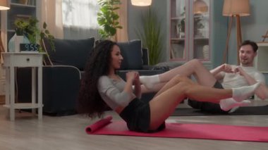 Sağlıklı sporcu çift, beyaz erkek, sporcu erkek, spor eğitmeni koca, İspanyol kadın, sporcu kadın, karın kasları spor egzersizi, bisiklet mekiği evde antrenman yapıyor.