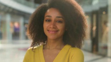 Genç Afro-Amerikalı kadın alışveriş merkezi kameraya bakıyor gülümseyen iş kadını öğrenci müşteri müşterisi kadınlık modeli moda, çok ırklı genç kıvırcık surat ifadesi mutlu neşe