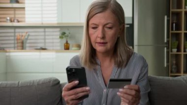 Kafası karışmış olgun Kafkasyalı yaşlı kadın bankacı kadın uygulama kullanıcısı kredi kartı kullanıcısı evde cep telefonu güvenlik sorunu olan üst düzey müvekkil yazarken kaşlarını çattı. Para kaybı dolandırıcılığı