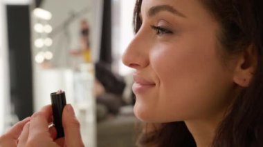 Neşeli beyaz kadın model kız ruj sürerek makyaj yapıyor. Makyaj yapıyor. Bayan dekoratif kozmetik ürünler kullanıyor. İçerideki blog stüdyosunda ayna profili görüntüsüne bakıyor.