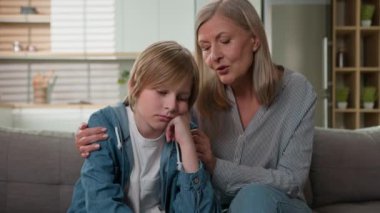 Kafkasyalı büyük anne kıdemli yaşlı kadın sinirleri bozuk, üzgün torun özür dileyen küçük çocuk özür diliyor çocuk aile sorunlarını kucaklıyor kanepe kavgası özür diliyor