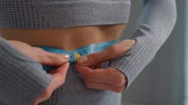 İnce, ince bir kadın spor kızı, bel ölçme bandı, bel ölçümü, bel ölçüsü, vücut ölçüsü, vücut ölçüsü, karın ölçüsü, zayıflatma, sağlık hizmeti zayıflaması, sağlıklı beslenme, spor salonu.