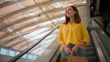 Neşeli, mutlu, beyaz, kadın, alışverişçi müşteri müşteri müşteri müşteri müşteri müşterisi. Bir sürü kağıt torba, alışveriş sonrası yürüyen merdivenlerin keyfini çıkar. Alışveriş merkezindeki havaalanı terminalinde merdivenleri kullan.