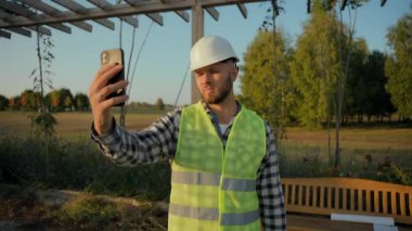 Kafkasyalı mühendis müteahhit, tamirci, cep telefonlu, fotoğraf çeken, fotoğraf çeken, inşaat projesi video kaydı olan, akıllı telefon parkından bahseden bir tamirci.