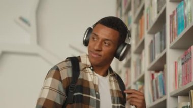 Kulaklıklı Afro-Amerikalı adam müzik şarkılarını dinliyor. Dansçı öğrenci, üniversite aletlerini öğreniyor. Kütüphane hazırlama oturumu.