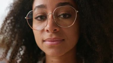 Afro-Amerikalı etnik kız öğrenci iş kadını bayan müşteri kameraya bakıyor kıvırcık saçlı, gözlüklü, gözlüklü, görüş sorunu olan, sağlık eğitimi alan, iş kadını.