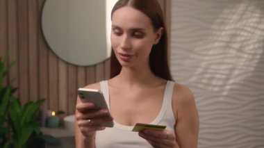 Beyaz, mutlu, gülümseyen bir kadın, banyo tatmin olmuş bir öpücük kredi kartı internet sitesine cep telefonu faturaları, internet üzerinden para harcayan e-ticaret alışverişi yaparak giriyor.