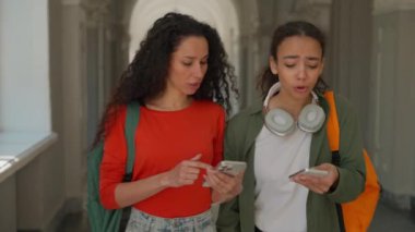 İki öğrenci kız kadın kadın kadın çok ırklı arkadaşlar kampüs yürüyüşüne çıkıyorlar akademi üniversitesinde cep telefonlu bir kadınla konuşuyorlar.