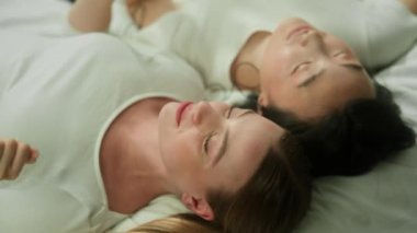 Çok ırklı arkadaşlar, çok ırklı kadınlar, Kafkasyalı kadın, Asyalı kadın, gözleri kapalı, yatak odasında dinleniyor, telli kulaklıkla müzik dinliyor, internette dans eden arkadaşlık radyosunun keyfini çıkarıyorlar.