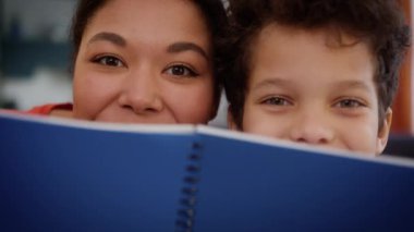 Afro-Amerikan mutlu aile annesi anne kadın öğretmen kız bakıcı öğretmen çocuk bakıcısı çocuk bakıcısı küçük oğlan çocuğu kitaptan gizlenen tebessümle dişlek sağlık dersini kandırarak