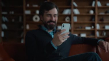 Şaşırtıcı bir şekilde yetişkin Kafkasyalı erkek, erkek işadamı cep telefonu şokuna bakıyor akıllı telefon başarısını kullanarak başarılı bir şekilde kapalı ofis içinde şanslı bir SMS mesajı aldı.