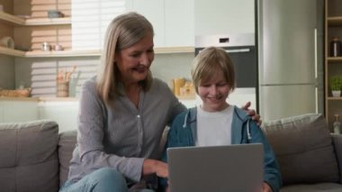 Mutlu, beyaz bir kadın, emekli, yaşlı bir kadın, yaşlı bir kadın, kucak dolusu çocuk, dizüstü bilgisayar eğitimi alan küçük bir çocuk, internet üzerinden alışveriş yapan, gülümseyen bir aile.