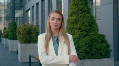 Kendine güvenen, beyaz, sarışın, iş kadını, resmi takım elbiseli bir öğrenci şehir merkezindeki kameraya bakıyor. Mutlu bayan halkla ilişkiler müdürü kollarını çaprazlayan kız kafa sallama işinde başarılı.