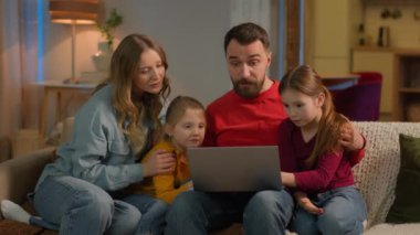 Aile babası çocuklar Kafkasyalı ebeveynler küçük kızlar hafta sonu evde kanepe üzerinde dizüstü bilgisayar alışverişi film bağımlısı bilgisayar oyunu bağımlıları kaybediyor.