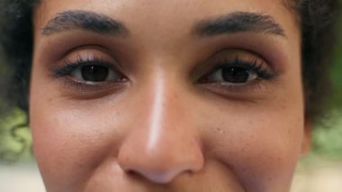 Kırpılmış manzara, kadın koyu renk gözleri görme lazer düzeltmesi, Afrikalı Amerikalı mutlu kadın, sağlıklı gülümsüyor, kameralı sağlık görevlisi, kadın suratı, şehrin dış kesimlerine bakıyor.
