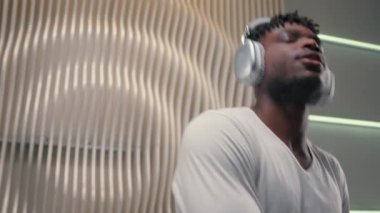 Genç Afro-Amerikalı, kulaklıklı aktif bir adam. Beyaz fütüristik odada enerjik müzik dinliyor. Kapalı kapılar ardında fütürizm yenilikçisi.