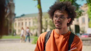 Afro-Amerikalı gülümseyen adam erkek öğrenci arkadaş kız arkadaş, kız arkadaş, kız arkadaş, iki öğrenci kardeş dışarıda eğitim hakkında konuşuyorlar.