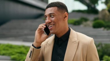 Mutlu gülümseyen Afro-Amerikan erkek girişimci işveren müdürü işveren iş adamı şehir işadamı arkadaş canlısı konuşan cep telefonu akıllı telefon konuşmaları konuşma