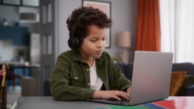 Afrika kökenli Amerikalı erkek çocuk bebek çocuk çocuk kulaklıkla kulaklık takıyor, video oyunu oynuyor, internet bağımlılığı dizüstü bilgisayar kullanıyor müzik dinleyip eğleniyor.