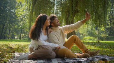 Mutlu, çok ırklı çift, kadın, Hintli erkek, gülümse. Konuşan, video, cep telefonu ortakları. Aile, erkek, foto, selfie, park, battaniye randevusu yapıyor.