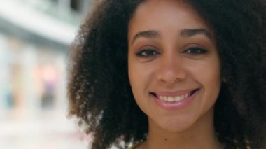 Kıvırcık Afrikalı Amerikalı etnik kadın örnek iş kadını dişlek dişli, dişlek, alışveriş manyağı tüketici modası mutlu bir bayan kameraya bakıyor.