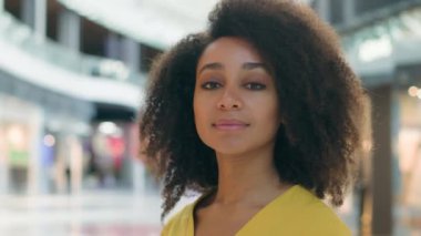 Afro-Amerikalı bir kadın kameraya bakıp başını çevirir. Mutlu, mutlu, mutlu, mutlu, mutlu, alışveriş merkezinden memnun, genç, hafta sonu mankeni, gevşemiş, güler yüzlü, pozitif yüz duygusu.