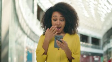 Cep telefonu akıllı telefonu kullanan mutlu Afrikalı Amerikalı kadın. Neşeli kadın gülüşü. Teknoloji zaferinin kazananı şaşırdı.