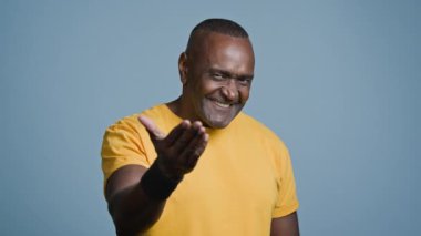 Çekici, Afro-Amerikan sporcu, sporcu, sporcu, spor eğitmeni. Stüdyoda mavi arka planda spor reklamları yapıyor. Erkek sporcuların eğitime davet edildiği kameraya gülümsüyor.