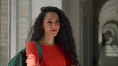 Portre mutlu gülümseyen pozitif İspanyol kadın kameraman kız Latin bayan öğrenciye bakıyor lisede kampüs akademisi koridorunda el ele eğitim öğreniyor.