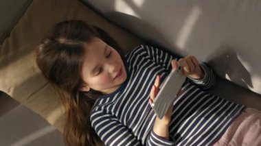 Kafkasyalı küçük bir kız elinde cep telefonu, akıllı telefon aygıtı, mesajlaşıyor, çocuk sohbet çocuğu, kız, internet ağlarını dinliyor, teknolojiye bağlı ev dokunmatik ekranı web sitesi.