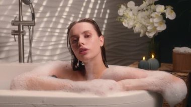 Beyaz kadın spa mumlarında dinleniyor. Küvet güzellik prosedürü. Nemlendirici köpük, köpük ve köpük.