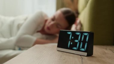 Sinirli bir kız sabah erken saatte uyanıyor yatak odasında stres uykusuzluk, uykusuzluk, uykusuzluk, uykusuzluk, uykusuzluk kadın öfke, öfke, yüksek sesli çalar saat sesi.