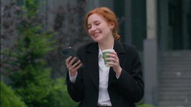 Neşeli, gülen, beyaz, kızıl, iş kadını, kadın, yönetici, müşteri elleri cep telefonu ağı kullanıyor, internette mesaj yazıyor, internette geziniyor, şehir dışında kahve içiyor.