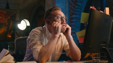 Gece ofisindeki stresli iş adamı çok çalıştı. Sorunlu iş adamı. Monitördeki yapışkan notlara bakıyor.