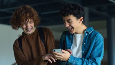 Üniversiteye geri dönelim. Kafkasyalı iki genç öğrenci. İnsanlar erkek arkadaşlar gülüyor. Gülüyorlar, cep telefonu kullanıyorlar.